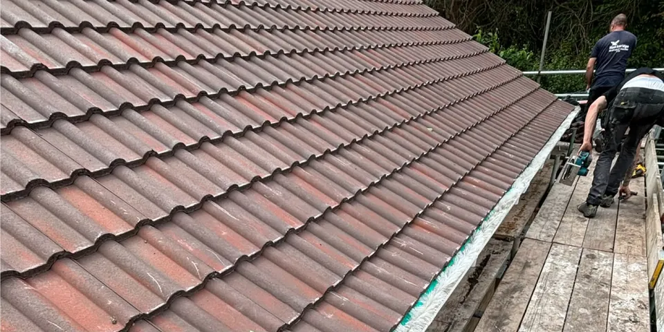 Roofer working on tiles at the eaves